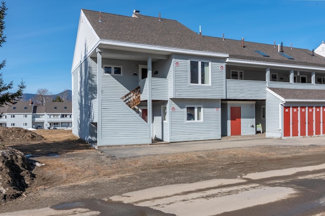 view of property with a balcony and roof with shingles