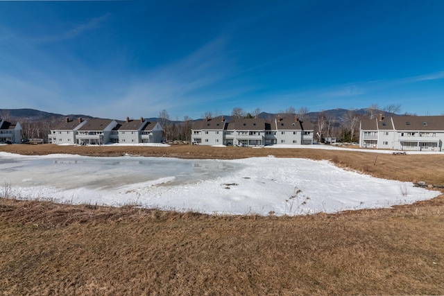 yard covered in snow featuring a mountain view and a residential view