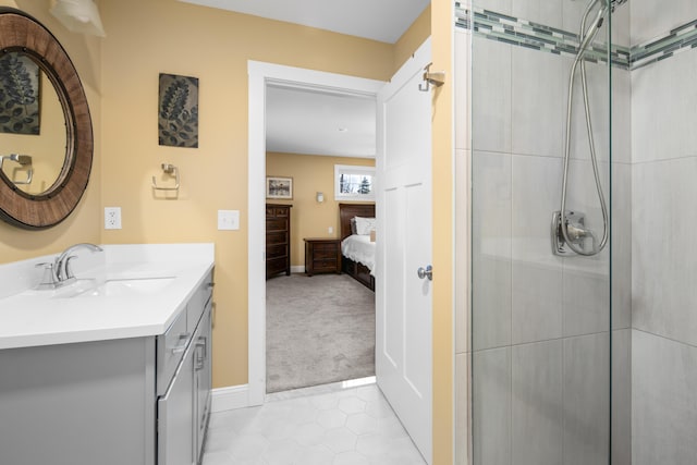 bathroom featuring ensuite bathroom, a tile shower, tile patterned flooring, baseboards, and vanity