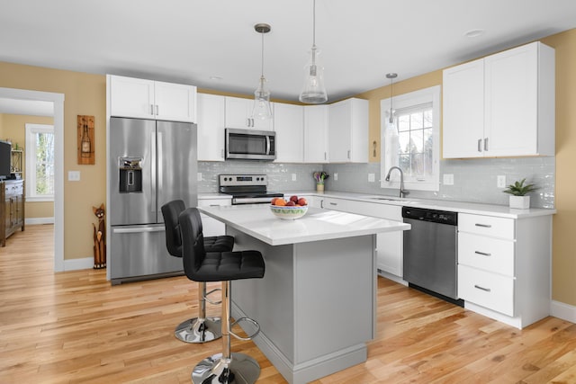 kitchen featuring appliances with stainless steel finishes, white cabinetry, light countertops, and a sink