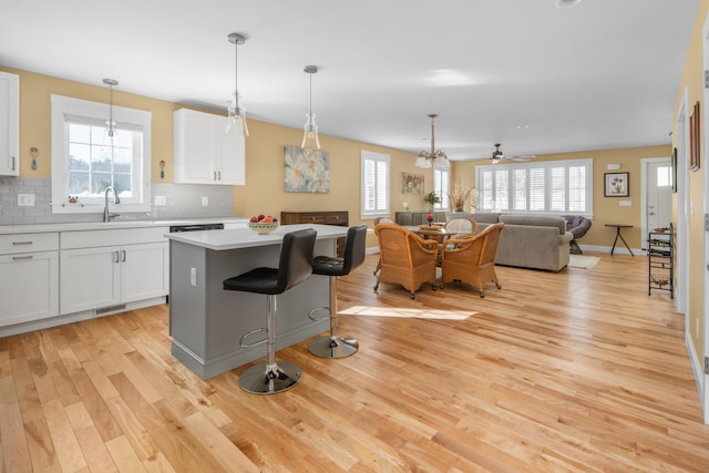 kitchen with decorative backsplash, a kitchen island, light countertops, and light wood finished floors