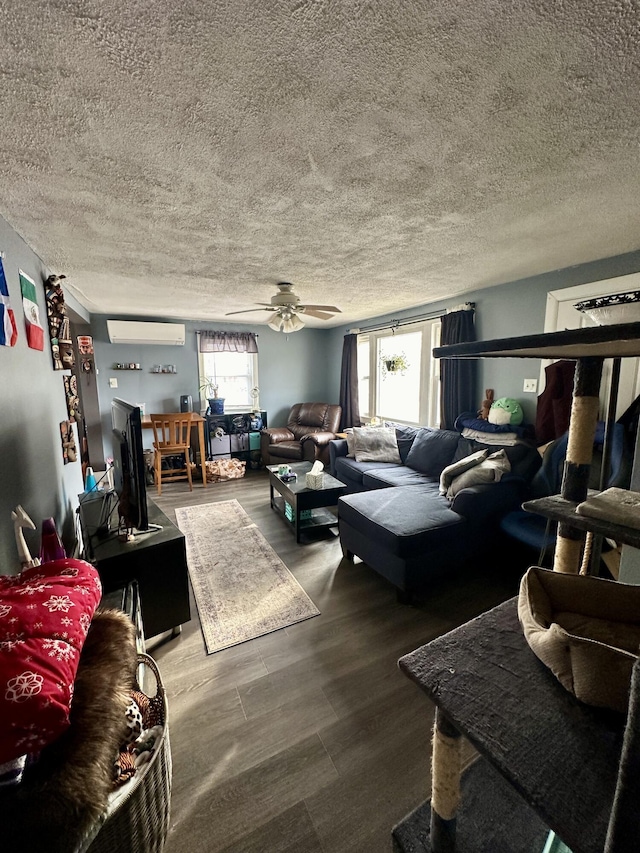 living room featuring wood finished floors, a textured ceiling, ceiling fan, and a wall unit AC