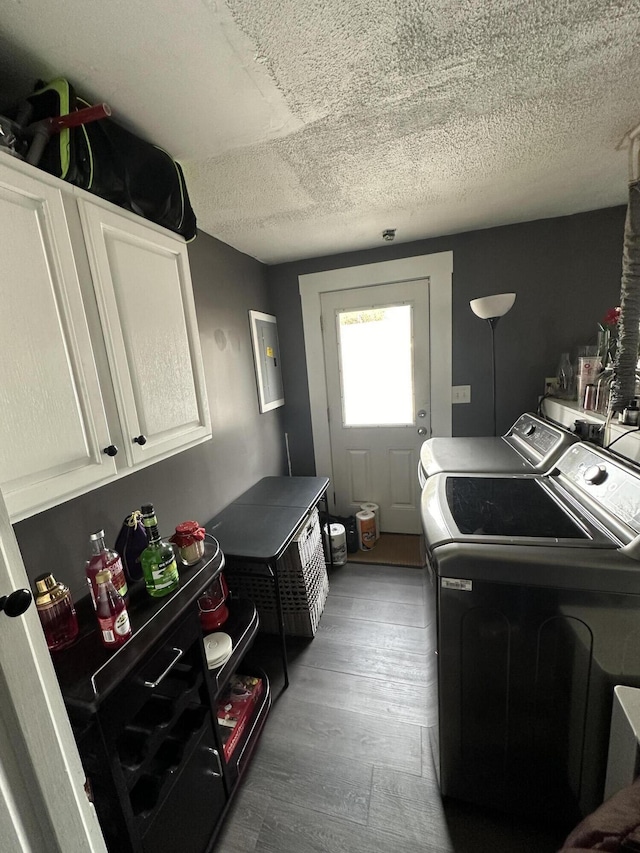 clothes washing area featuring cabinet space, wood finished floors, independent washer and dryer, and a textured ceiling