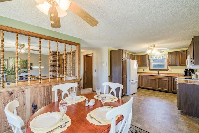 dining area featuring a ceiling fan and a textured ceiling