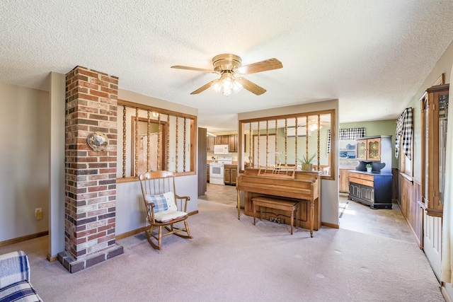 living area featuring baseboards, light carpet, a textured ceiling, and ceiling fan