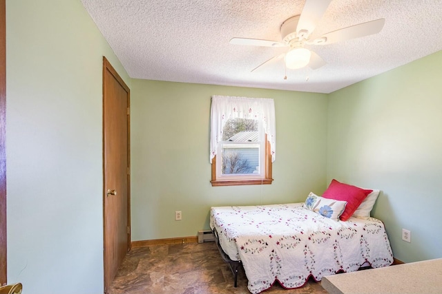 bedroom featuring a baseboard heating unit, a textured ceiling, ceiling fan, and stone finish flooring