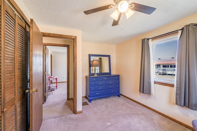 bedroom featuring baseboards, light carpet, a closet, and ceiling fan