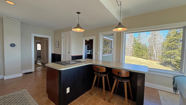 kitchen featuring baseboards, light countertops, decorative light fixtures, and electric stovetop