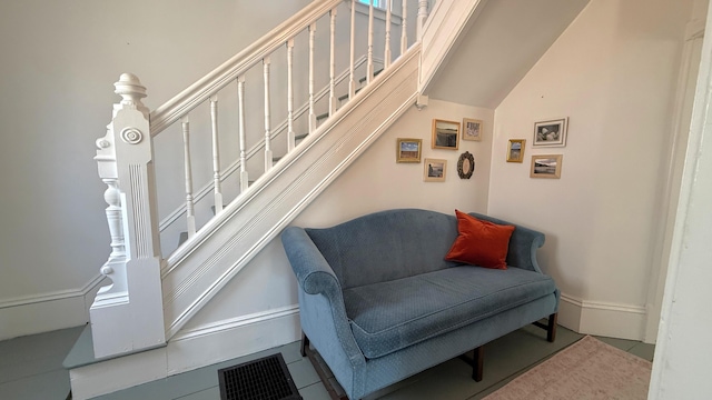 living area with lofted ceiling, visible vents, and stairway