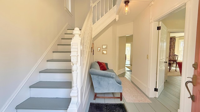 stairs featuring wood finished floors, a healthy amount of sunlight, and a towering ceiling