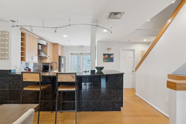 105 Chandlers Wharf Unit 105, Portland, ME 04101 - kitchen featuring wall chimney range hood, freestanding refrigerator, light wood-style floors, tasteful backsplash, and open shelves