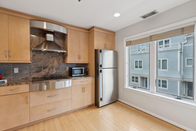 105 Chandlers Wharf Unit 105, Portland, ME 04101 - kitchen with appliances with stainless steel finishes, light brown cabinetry, wall chimney range hood, decorative backsplash, and recessed lighting