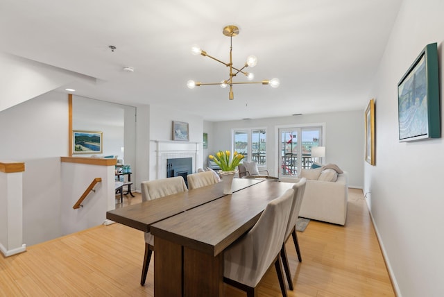 105 Chandlers Wharf Unit 105, Portland, ME 04101 - dining room with light wood-style flooring, a chandelier, a fireplace, and baseboards