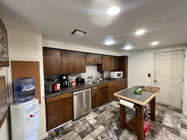 kitchen featuring dark countertops, white microwave, tasteful backsplash, a sink, and dishwasher