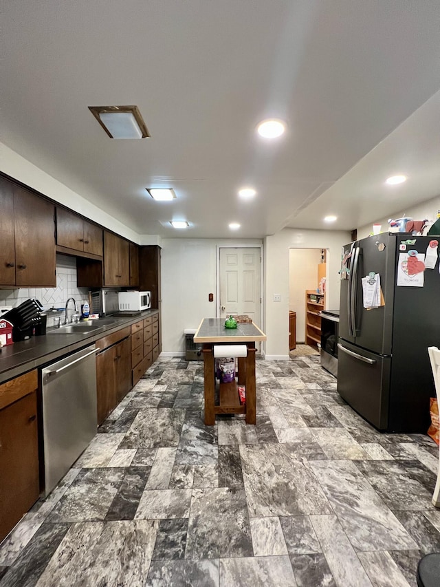 kitchen with decorative backsplash, dark brown cabinets, baseboards, a sink, and stainless steel appliances