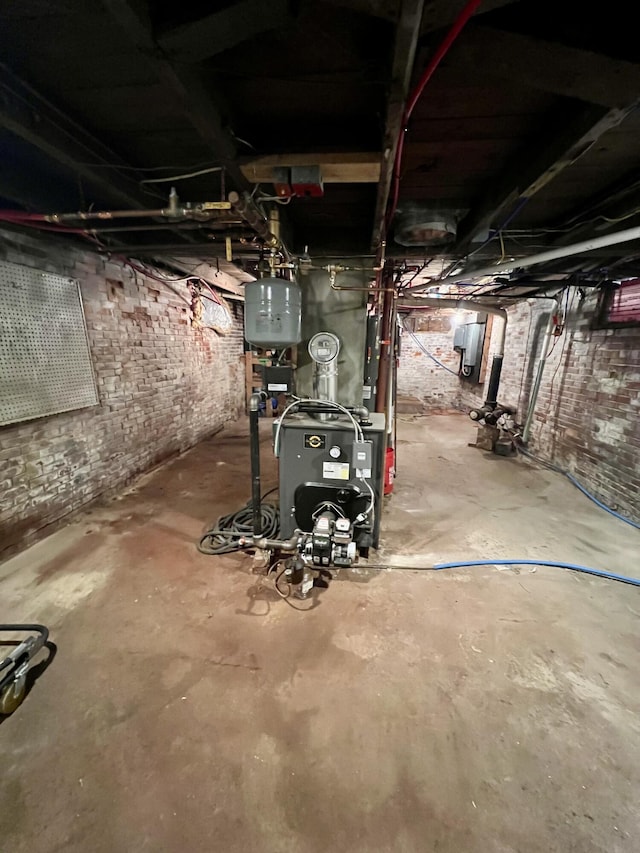 unfinished below grade area featuring a heating unit and brick wall