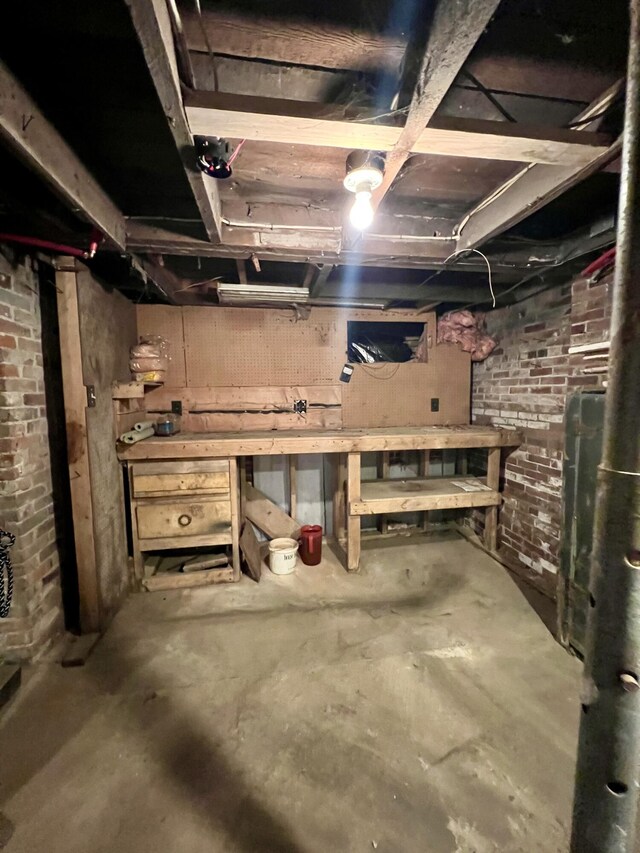 unfinished basement with a workshop area and brick wall