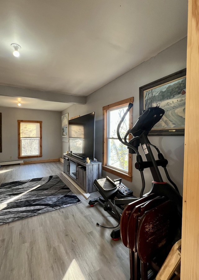 exercise room featuring wood finished floors, baseboards, and a baseboard heating unit