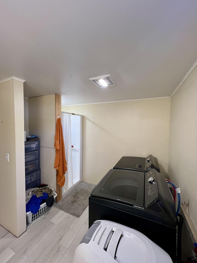 laundry room with washer and dryer, laundry area, wood finished floors, visible vents, and ornamental molding