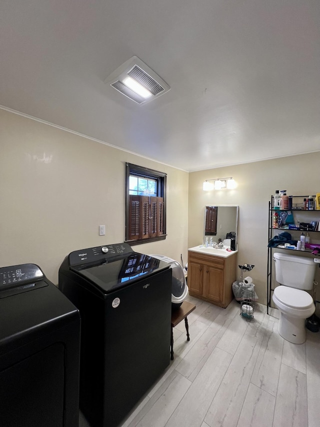 interior space featuring laundry area, crown molding, visible vents, washing machine and dryer, and light wood finished floors