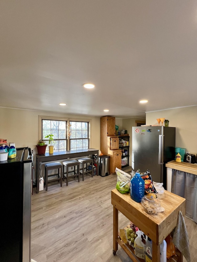 kitchen featuring light wood-style floors, freestanding refrigerator, brown cabinetry, and recessed lighting