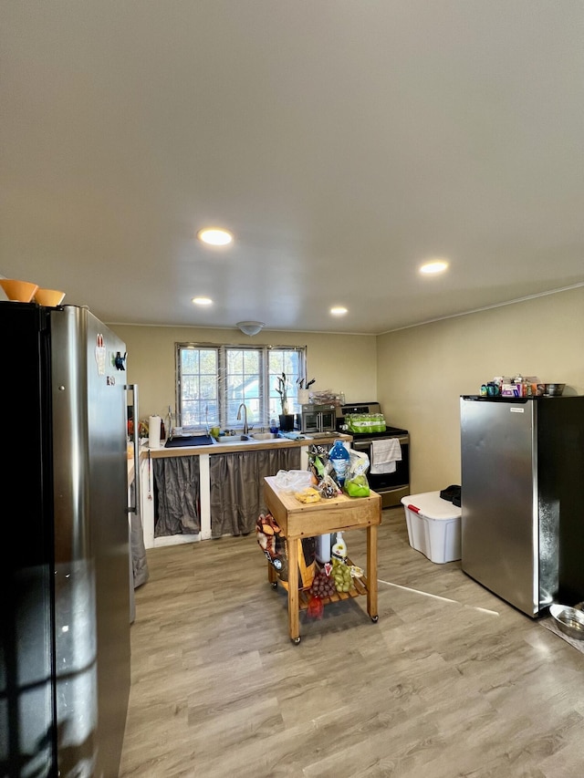 game room featuring light wood-type flooring, recessed lighting, and a sink