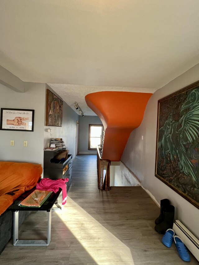 bonus room featuring baseboards, a baseboard heating unit, and wood finished floors