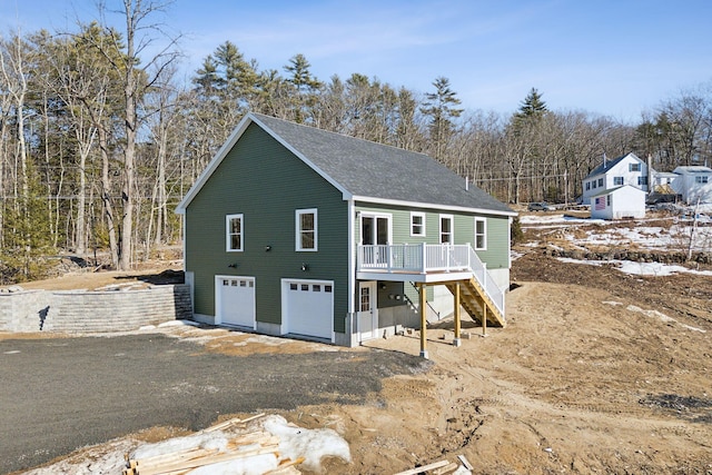 view of outbuilding with stairway, an attached garage, and driveway