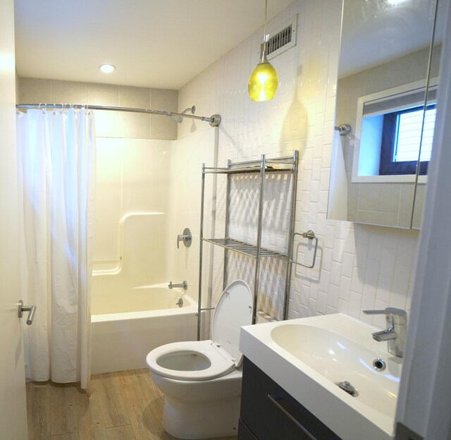 full bath featuring vanity, wood finished floors, visible vents, tile walls, and shower / tub combo with curtain