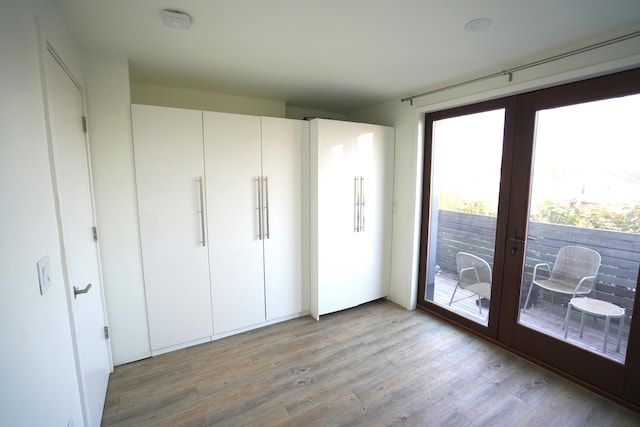 unfurnished bedroom with french doors, access to exterior, and light wood finished floors