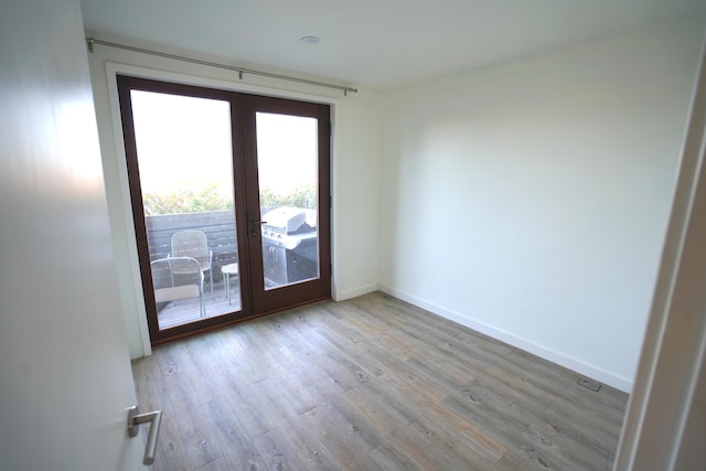 spare room with baseboards and wood finished floors