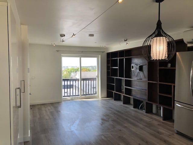 unfurnished living room with baseboards, an inviting chandelier, and wood finished floors