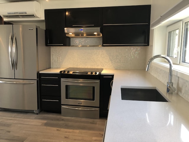 kitchen with a sink, range hood, stainless steel appliances, light countertops, and dark cabinets