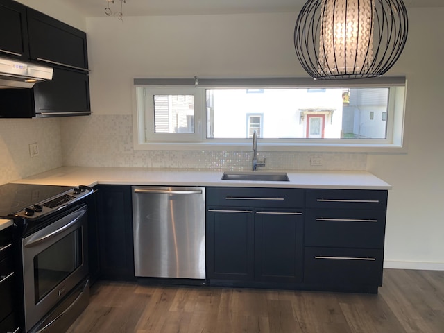 kitchen with a sink, appliances with stainless steel finishes, wood finished floors, and light countertops