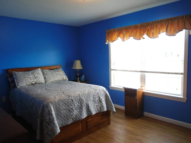 bedroom with wood finished floors and baseboards