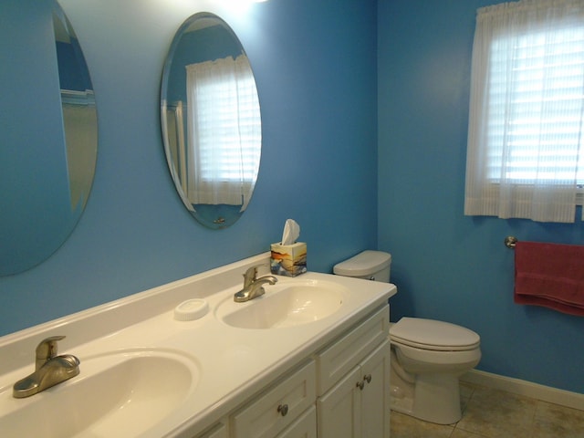 full bath with tile patterned flooring, double vanity, toilet, and a sink