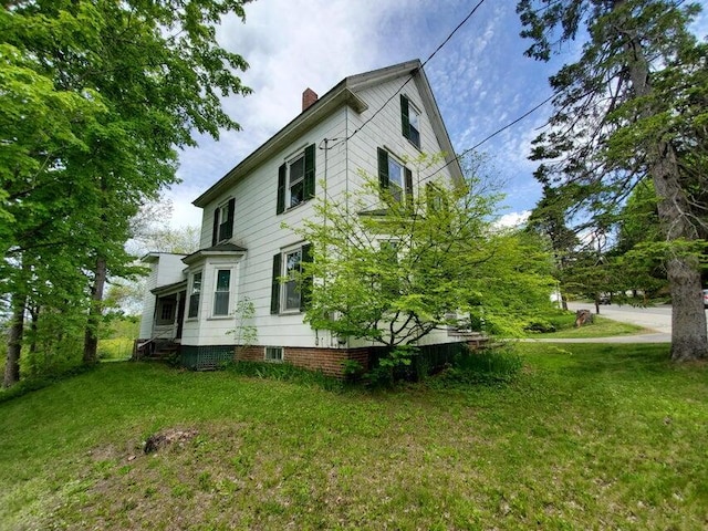 view of side of home featuring a chimney and a yard