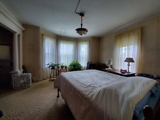 carpeted bedroom with crown molding and decorative columns