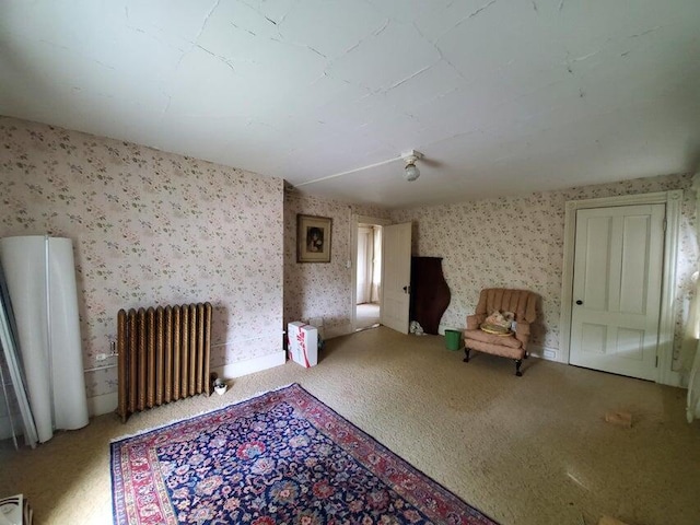 unfurnished room with wallpapered walls, radiator, and carpet flooring