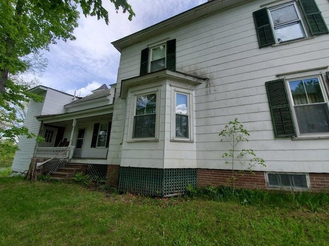 view of side of property featuring covered porch and a yard