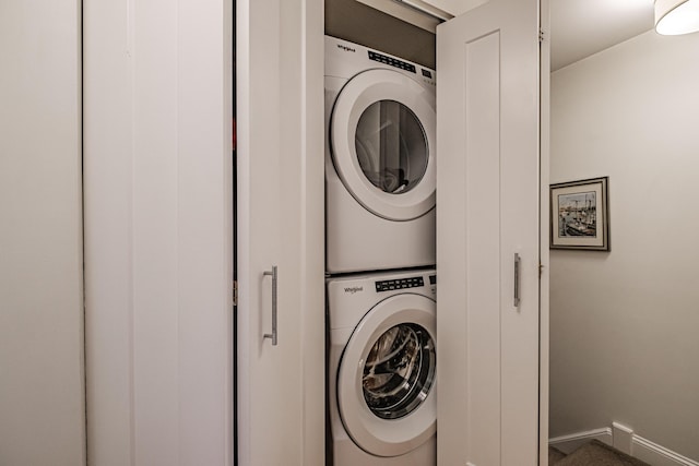 laundry room with baseboards, stacked washer and clothes dryer, and laundry area