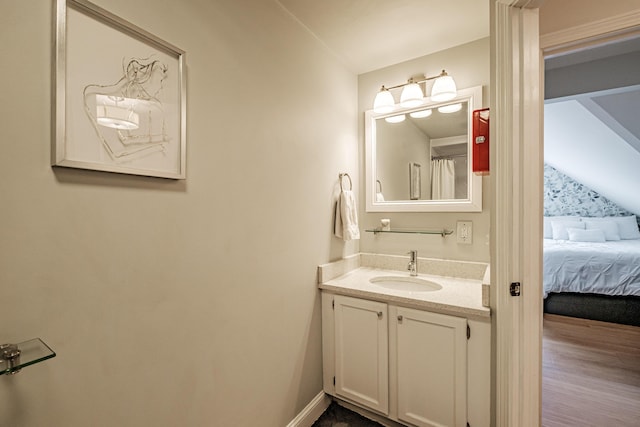 bathroom with vanity, wood finished floors, baseboards, and connected bathroom