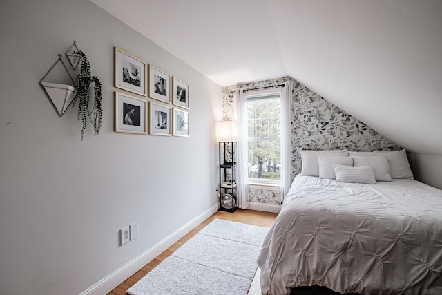 bedroom featuring baseboards, wood finished floors, and vaulted ceiling