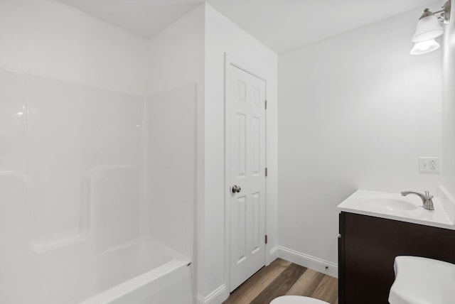 bathroom featuring baseboards, toilet, wood finished floors, and vanity