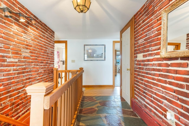 11 Elm Dr, York, ME 03909 - hallway featuring brick wall, an upstairs landing, stone tile floors, and baseboards