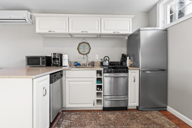 kitchen featuring white cabinetry, appliances with stainless steel finishes, a wall mounted air conditioner, and a sink