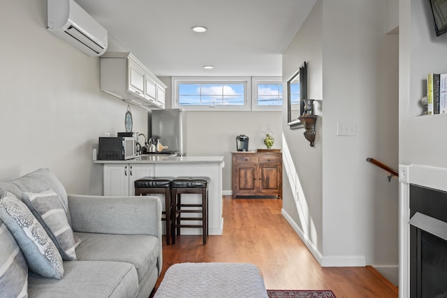 living room with light wood-style flooring, a wall mounted air conditioner, and baseboards