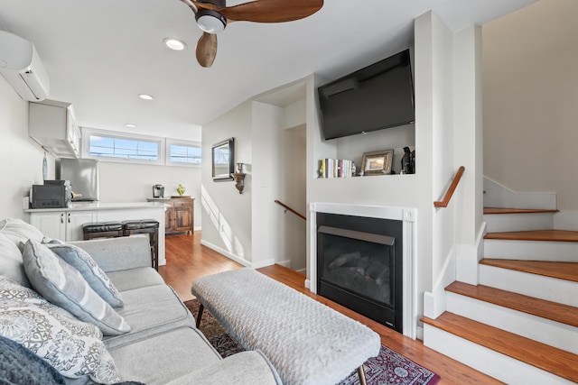 living area with baseboards, recessed lighting, ceiling fan, an AC wall unit, and light wood-type flooring