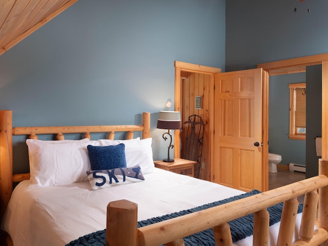 bedroom with a baseboard heating unit, wood finished floors, and high vaulted ceiling