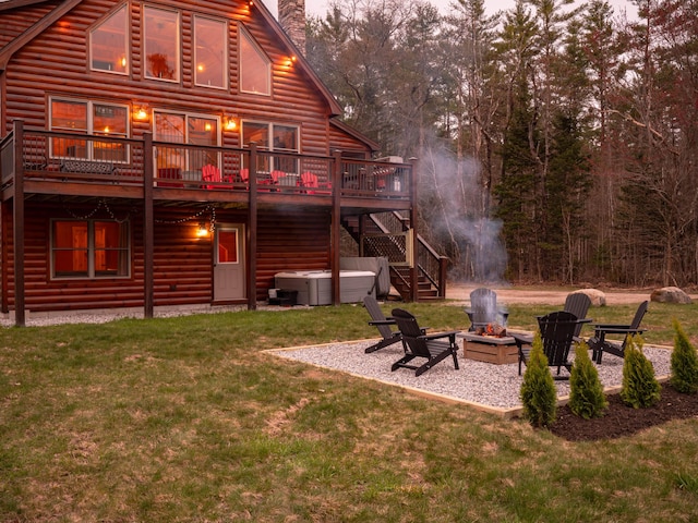 back of property featuring a patio, faux log siding, a fire pit, a chimney, and a hot tub